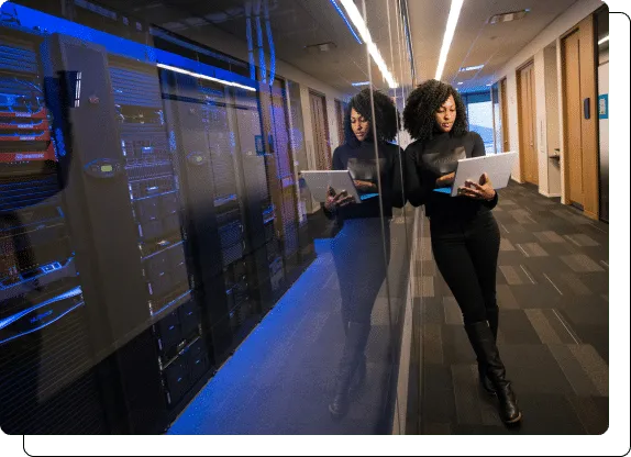 A woman with a tablet walking past server racks in a data center.