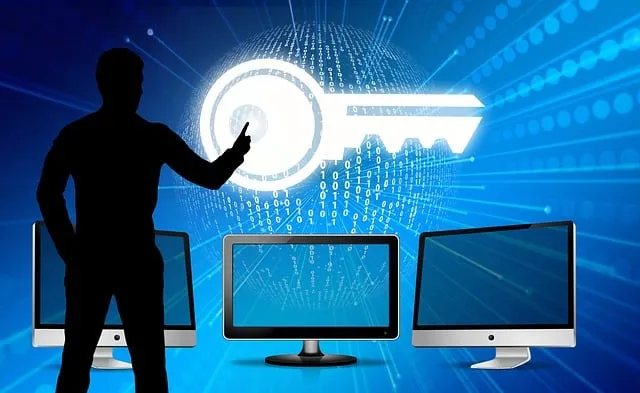 Silhouette of a person touching a digital key icon on a screen, with binary code and three computer monitors in the foreground.