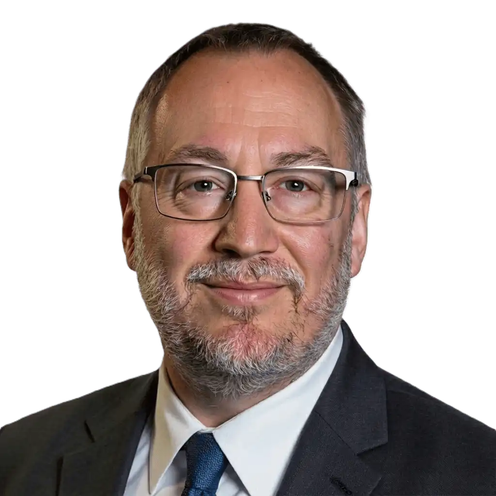 A middle-aged man with glasses, short gray hair, and a beard wearing a suit, tie, and collared shirt, posing against a plain white background.